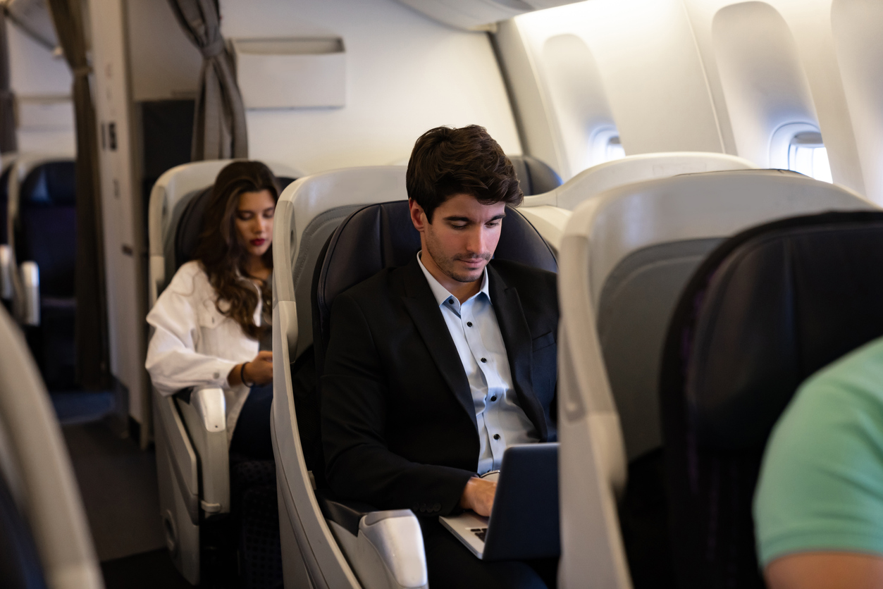Business traveler working on laptop in business class cabin, showing comfort and productivity with a travel consolidator deal