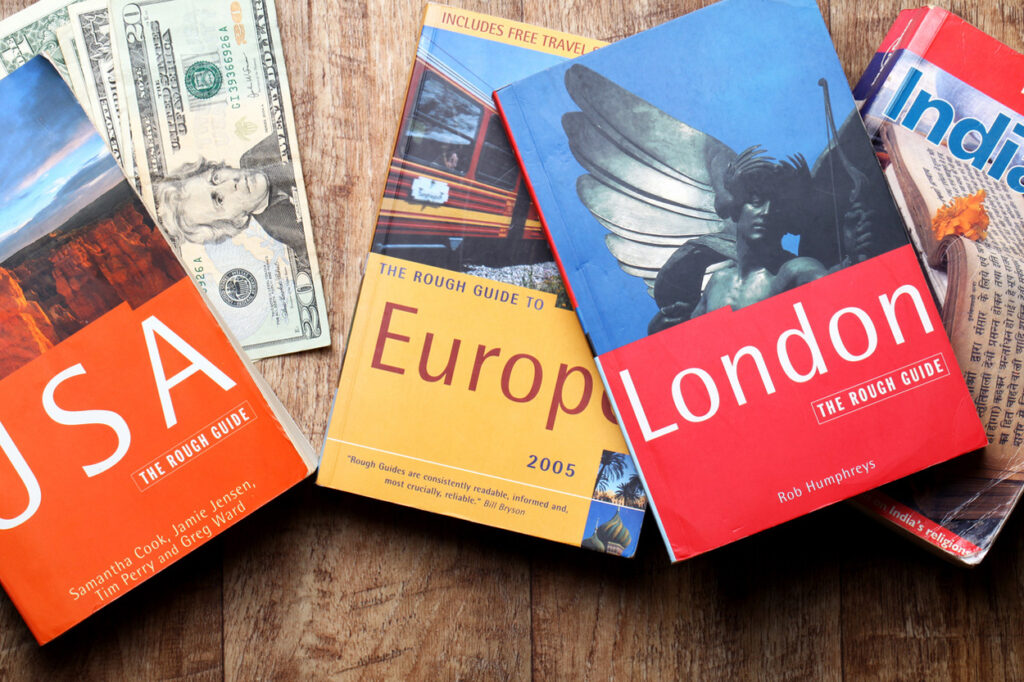 Travel planning concept with guidebooks and cash for new destinations in USA, Europe, London, and India