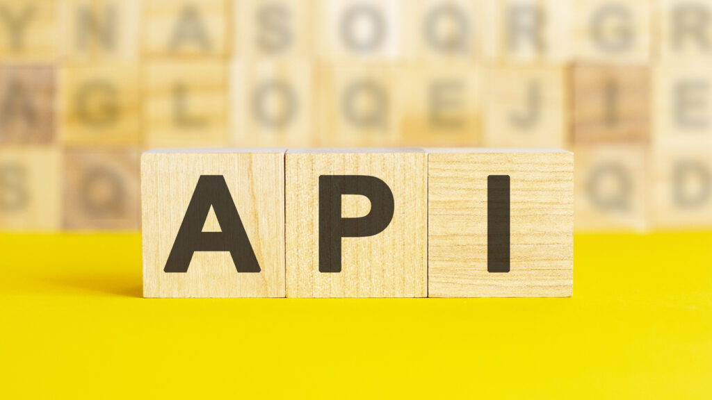 Wooden blocks spelling API on a yellow background, symbolizing Expedia API integration for travel booking, hotel search, and online reservation systems