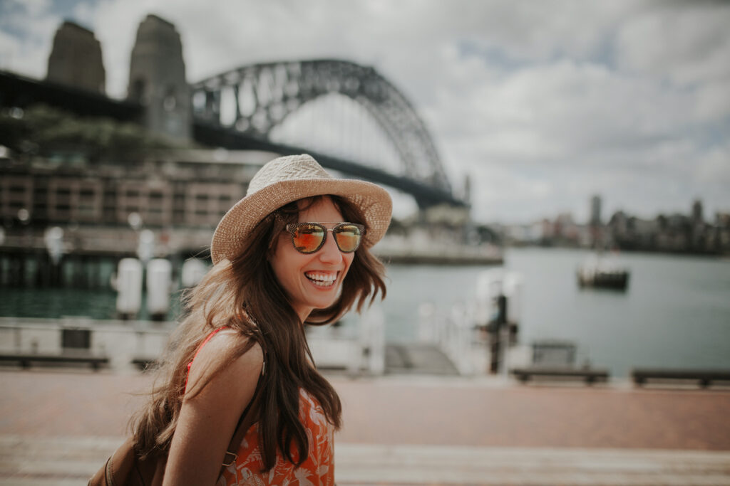 Smiling tourist wearing hat and sunglasses benefitting from booking through a hotel aggregator api